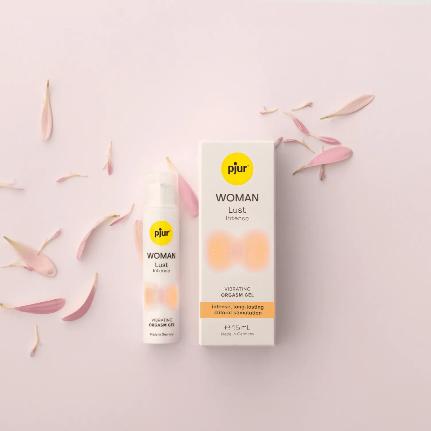 Pjur Woman Lust Intense orgasmegel i 15 ml flaske med tilhørende æske. Lifestyle produktbillede med blomsterblade, designet til intens klitorisstimulering, vibrerende effekt og sanselig wellness for kvinder.