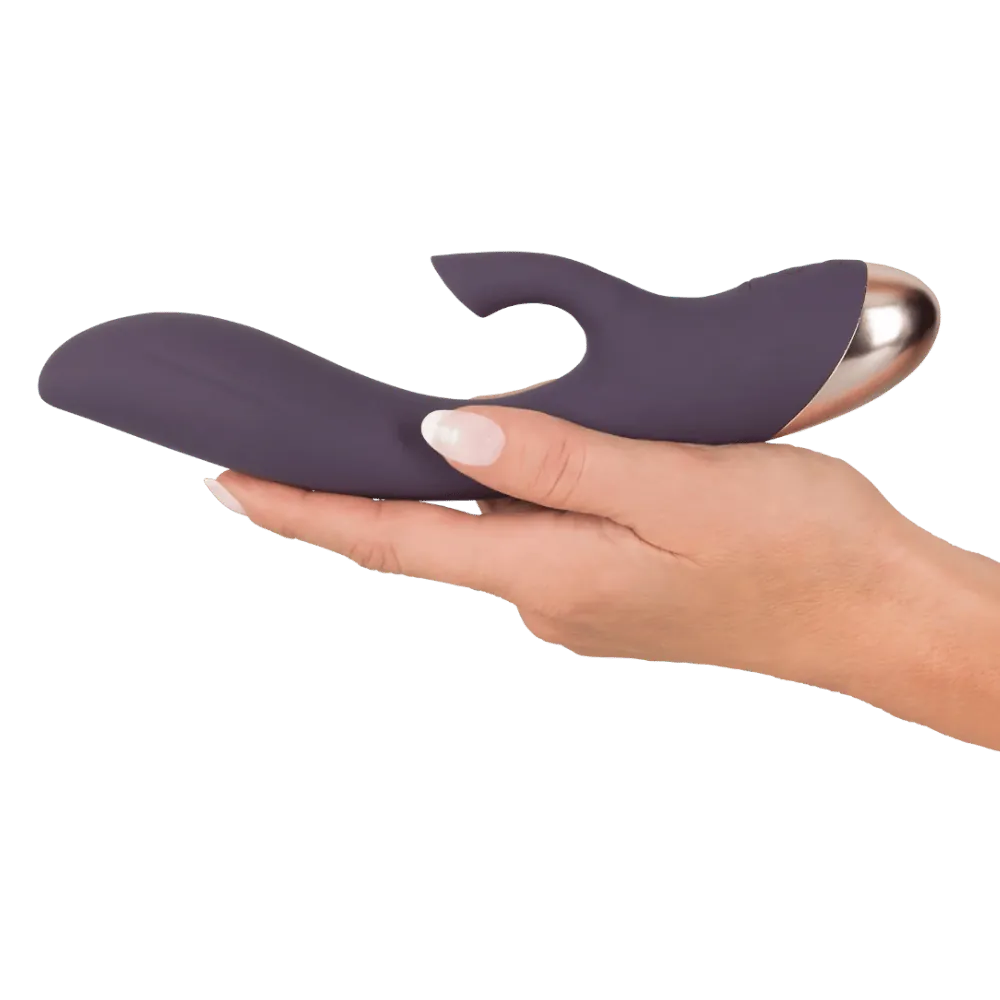 Elegant dobbeltstimulator i mat lilla silikone holdt i hånden, designet til samtidig G-punkts- og klitorisstimulering, ideel til sanselig selvforkælelse og moderne intim wellness.