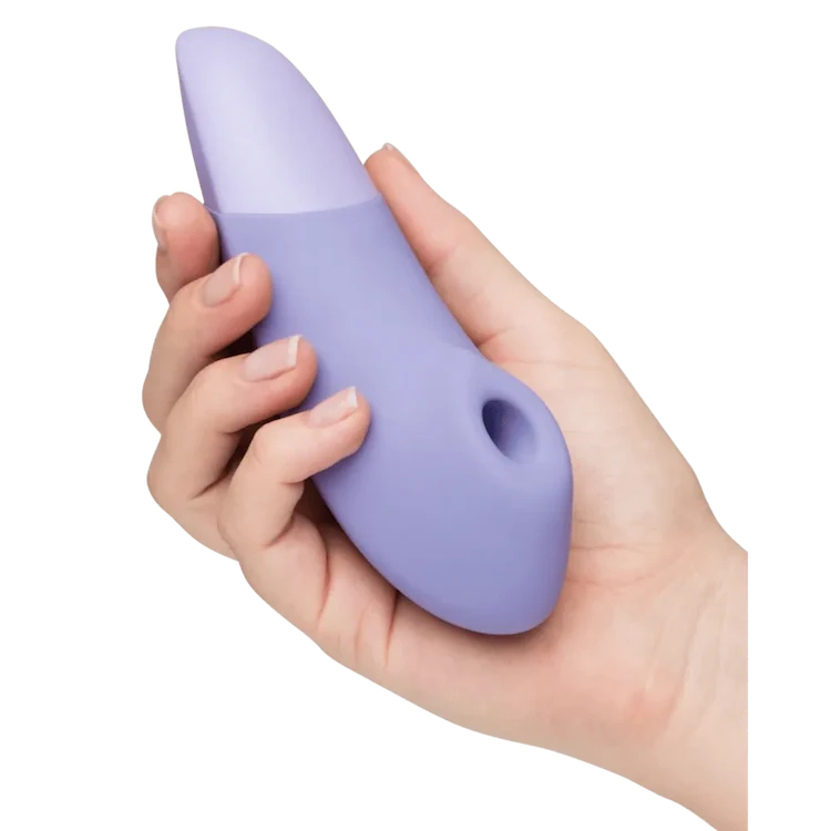 Produktbillede af Womanizer Enhance i elegant lilla nuance, holdt i en kvindes hånd. Intim vibrator med lufttryksstimulering, designet til sanselig nydelse, diskret brug og moderne wellness i hverdagen.