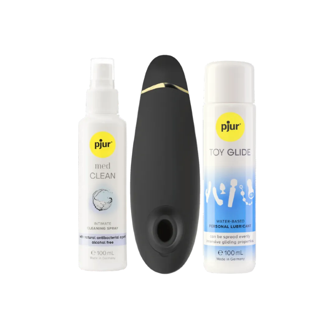 Womanizer Premium 2 lufttryksvibrator placeret mellem Pjur Toy Glide glidecreme og Pjur Med Clean rengøringsspray. Et komplet intimprodukt-sæt, der forener sanselig stimulering, plejende glideoplevelse og sikker rengøring til moderne erotisk wellness.