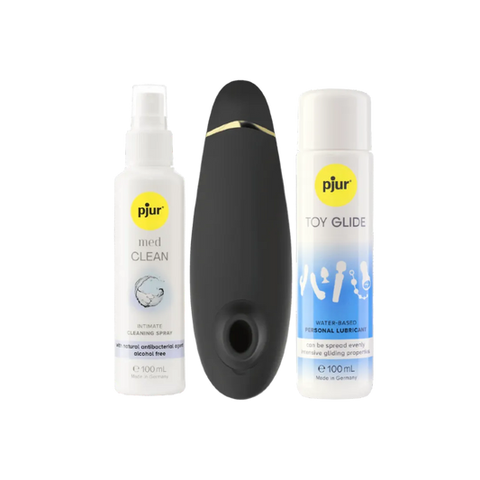 Womanizer Premium 2 lufttryksvibrator placeret mellem Pjur Toy Glide glidecreme og Pjur Med Clean rengøringsspray. Et komplet intimprodukt-sæt, der forener sanselig stimulering, plejende glideoplevelse og sikker rengøring til moderne erotisk wellness.