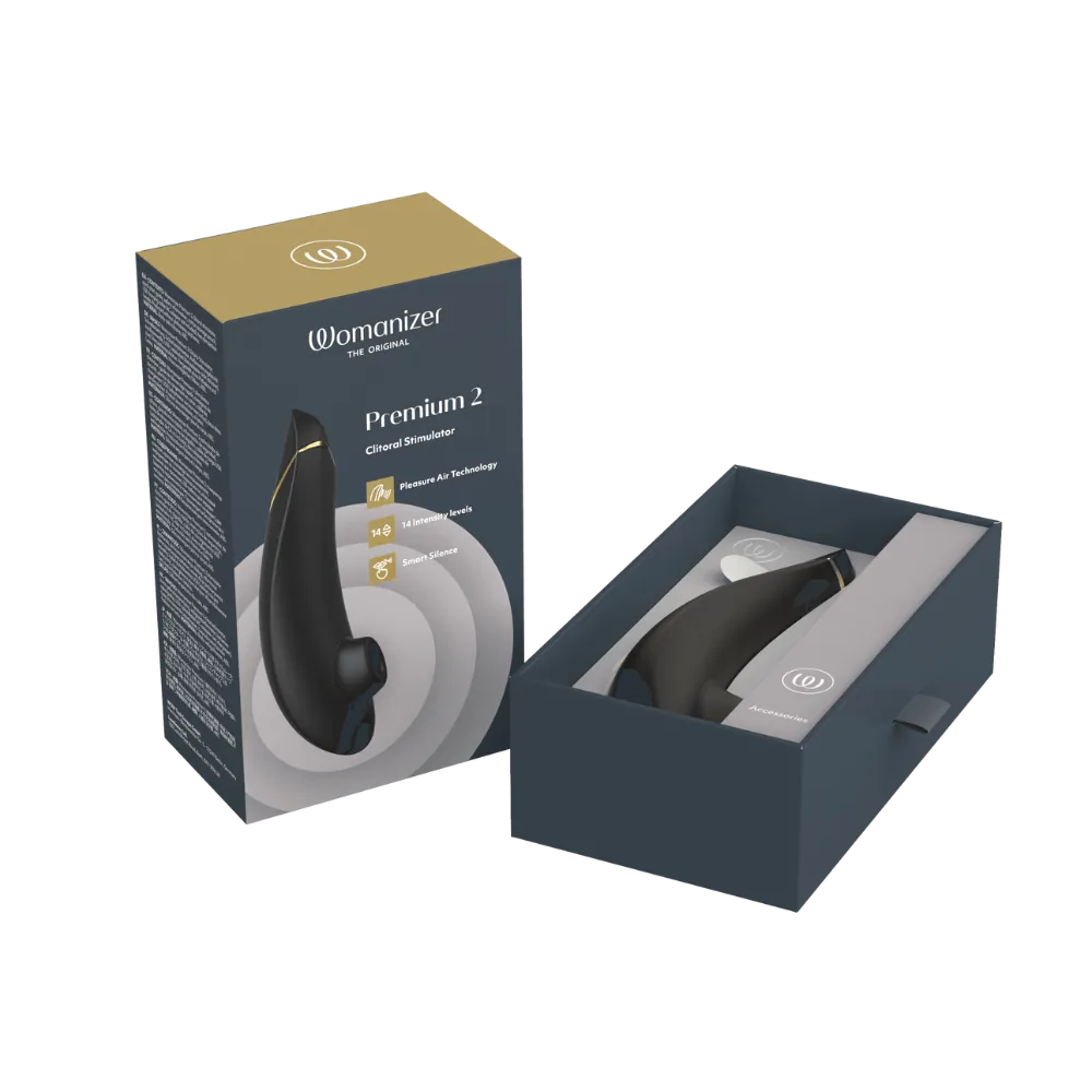 Womanizer Premium 2 clitoral stimulator i sort med gyldne detaljer ved siden af sin originale æske. Eksklusivt intimprodukt med Pleasure Air Technology og 14 niveauer af intens stimulering.